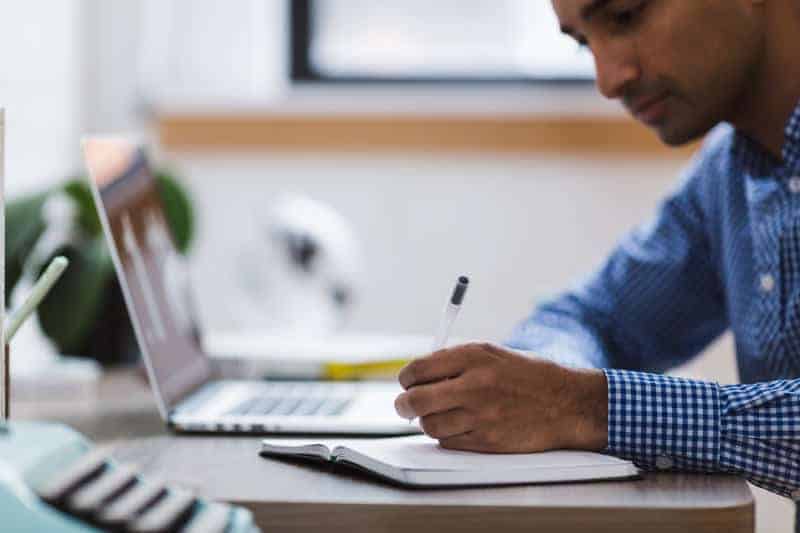 VSA Prospecting | Generating Leads Man writes in a notebook in front of his laptop
