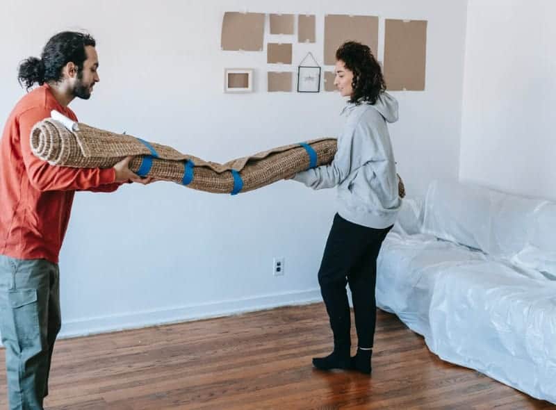 Two people carry a carpet to be installed