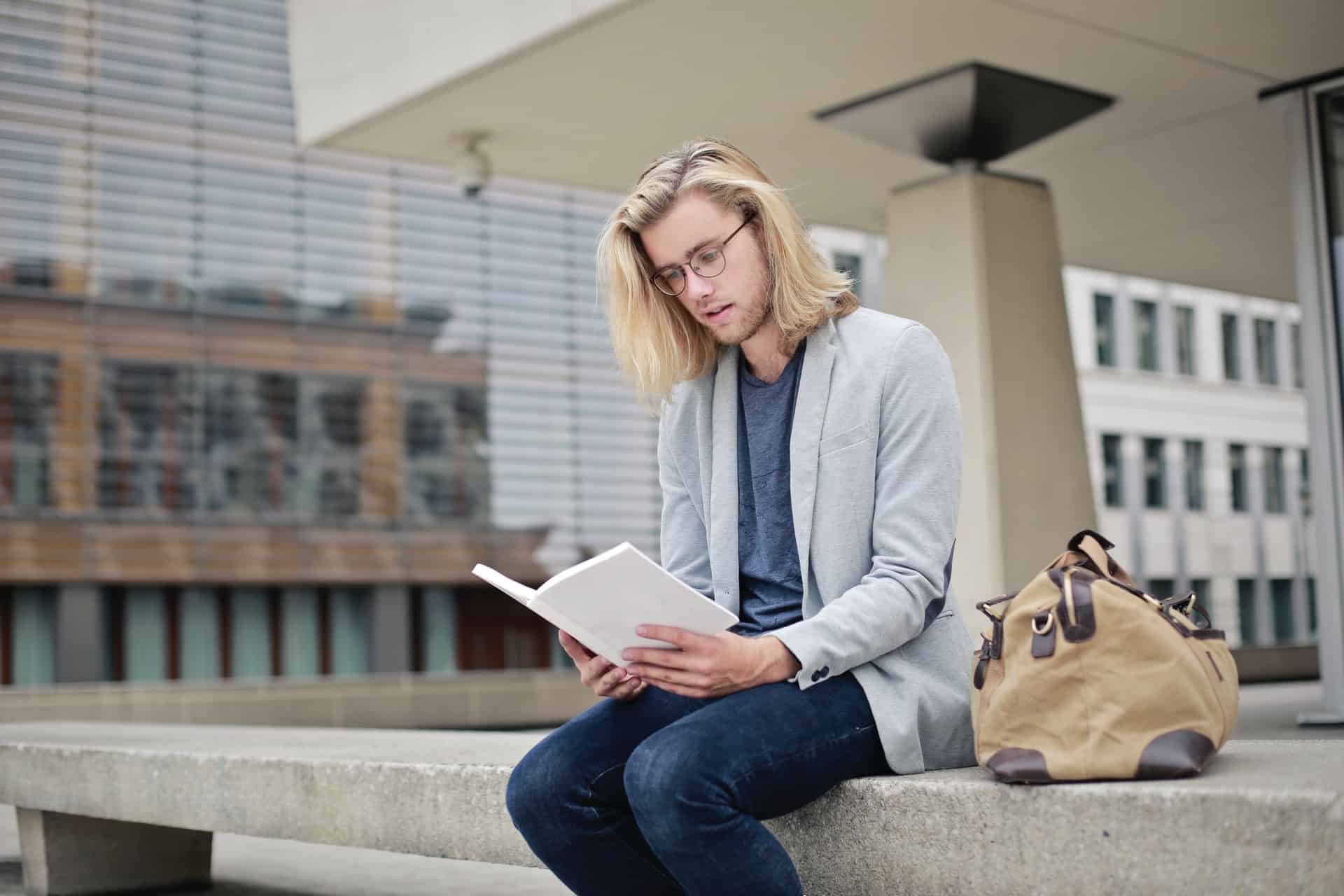 Man sitting on bench reading a book