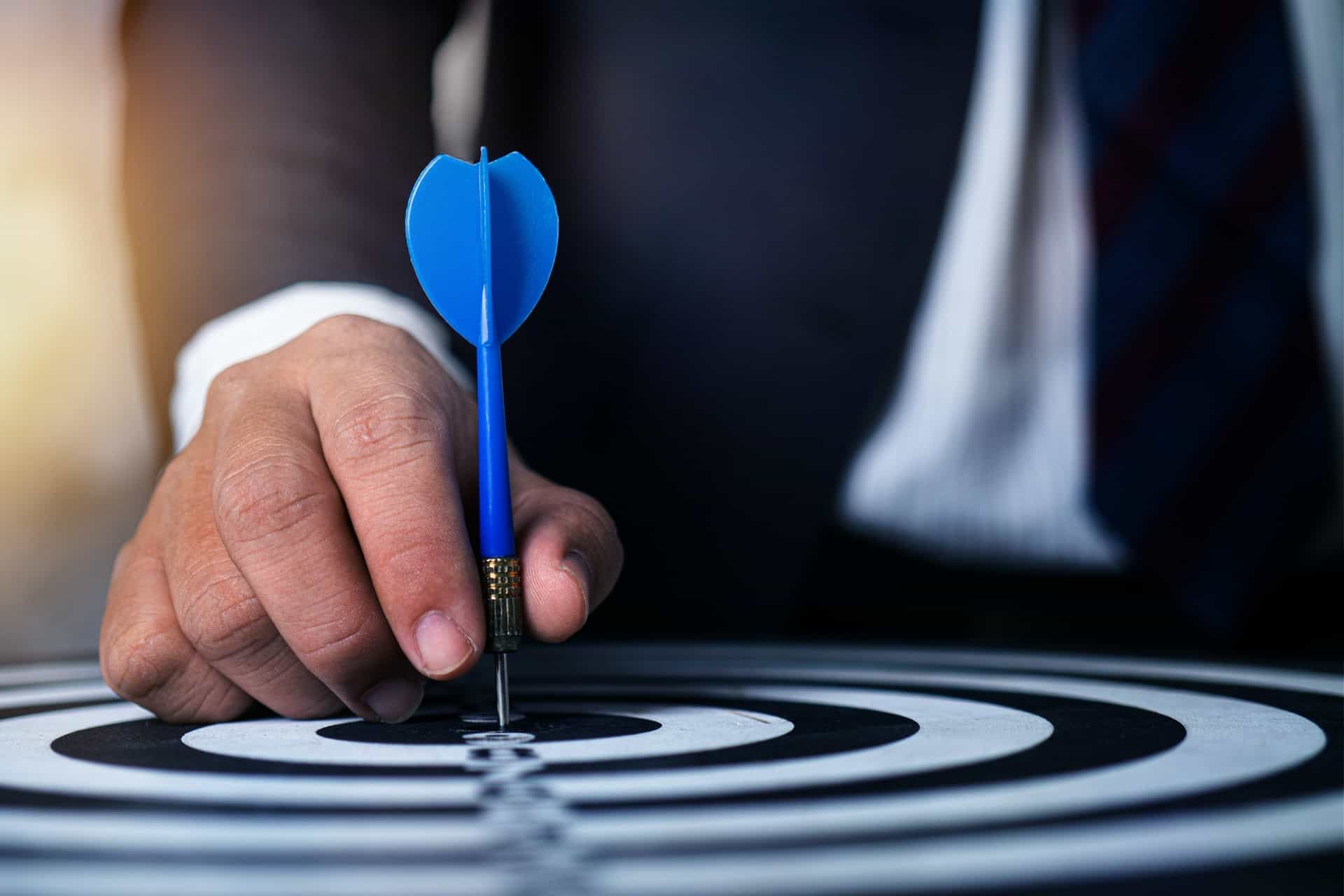 Man putting dart in center of target