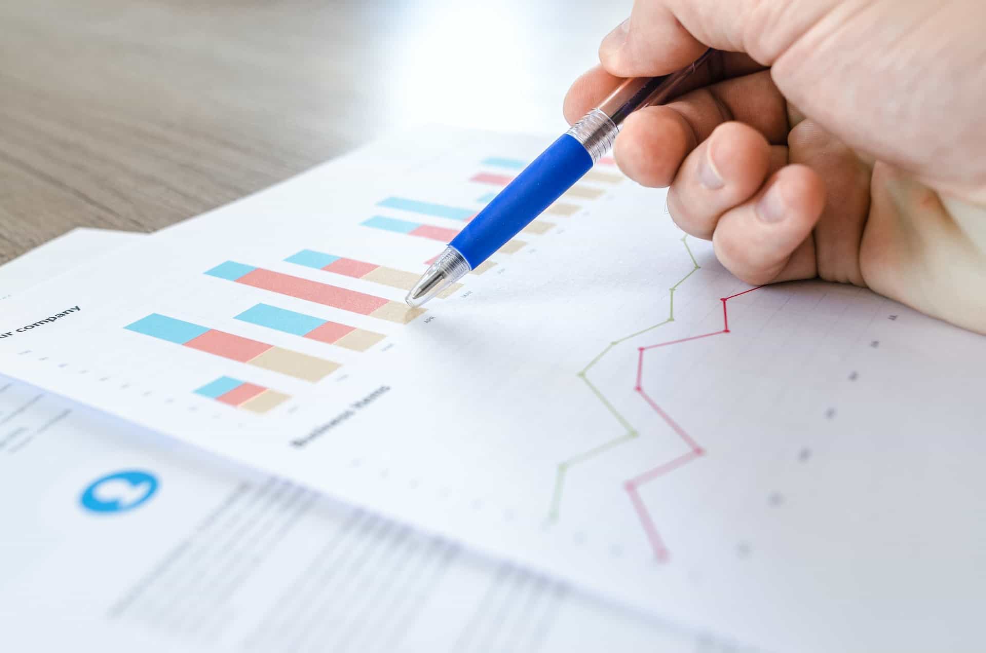 Pen on paper pointing to graphs and analytics